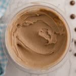 A bowl of ninja creami cottage cheese chocolate ice cream sits on a marble surface with a blue checkered napkin and chocolate pieces nearby.