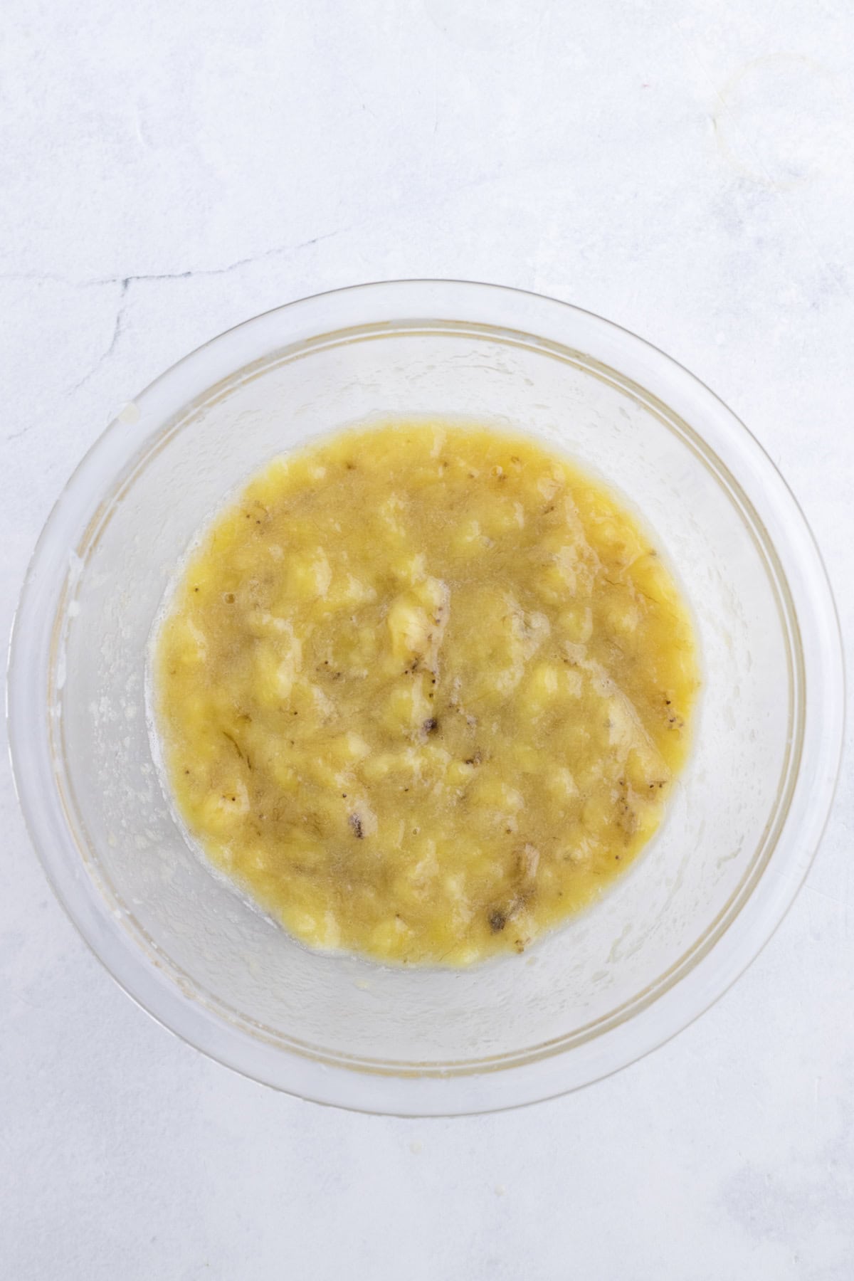 A glass bowl containing wet mix on a light-colored surface.