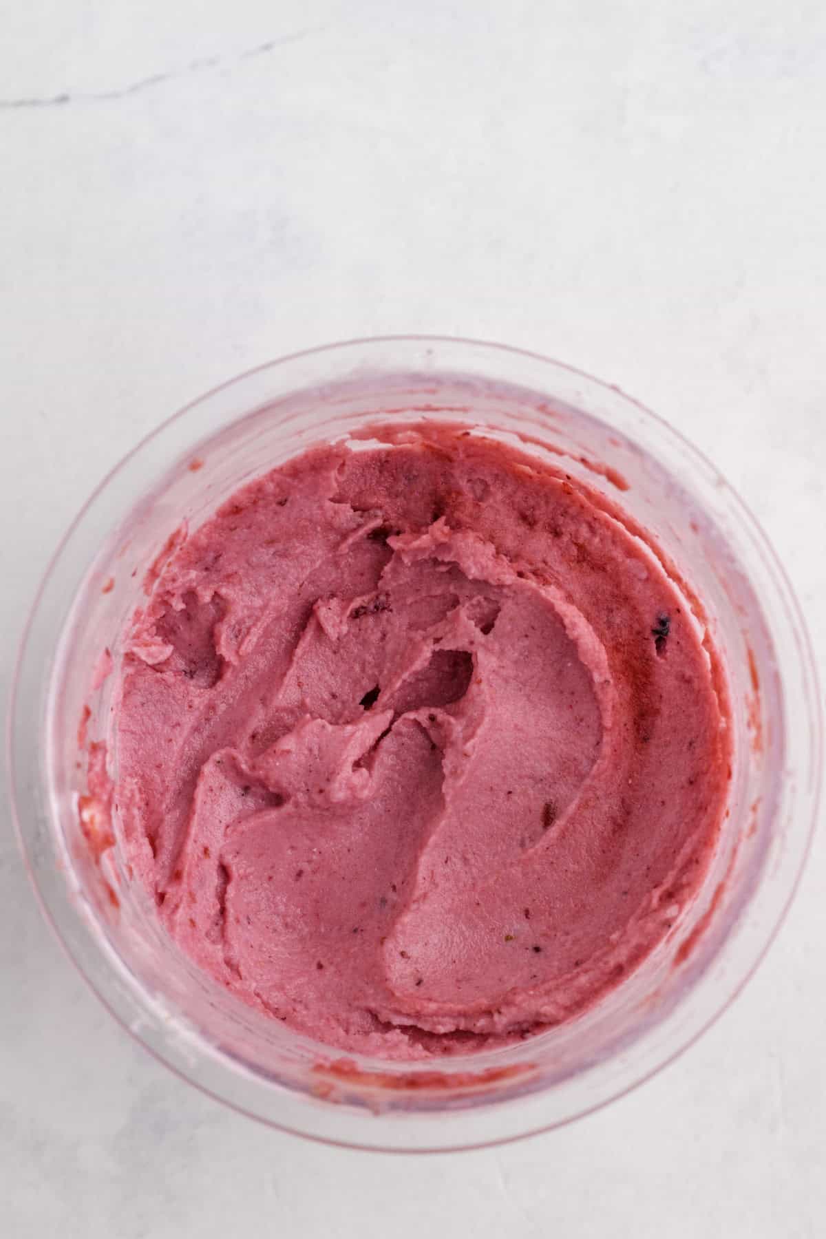 Un bol de mélange lisse de yogourt glacé aux fraises, sur une surface légère.