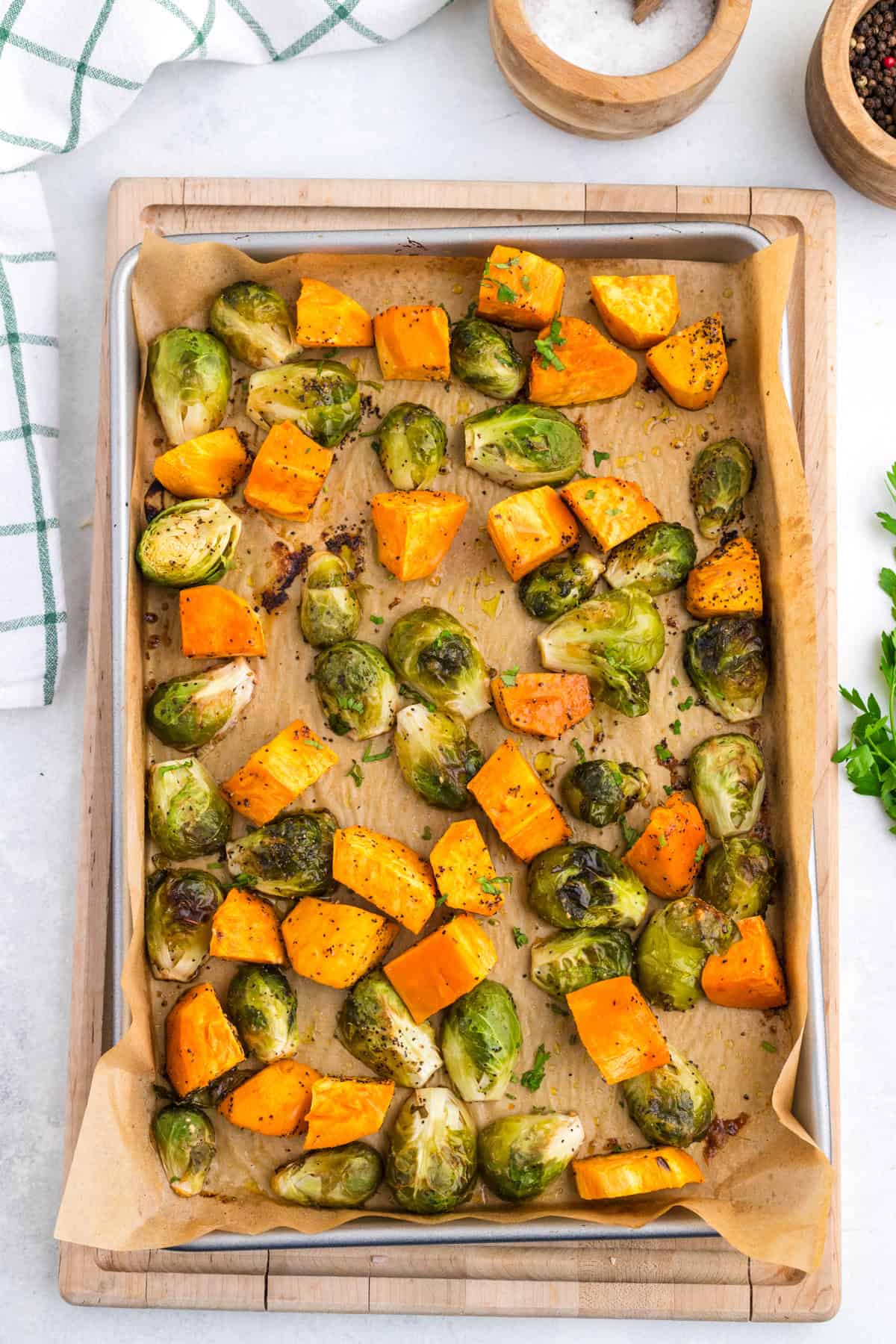 Roasted Brussels sprouts and sweet potatoes cooked on a parchment-lined baking sheet.